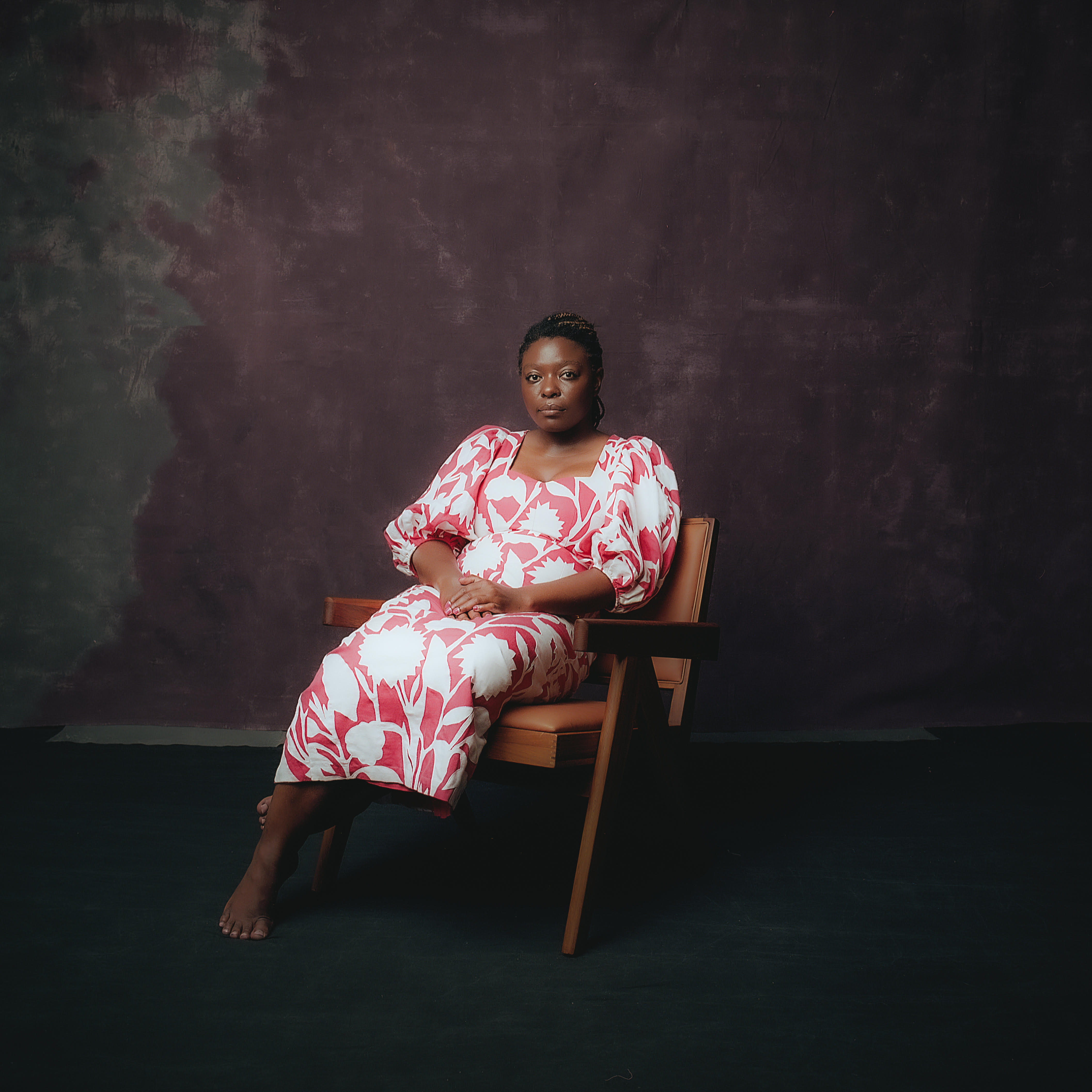 Black Woman sitting in a chair wearing a dress 
