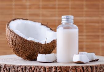 cosmetic bottle and fresh organic coconut for skincare, natural brown background