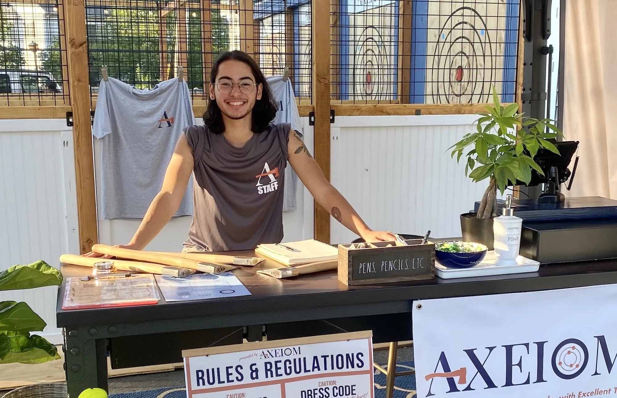 Staff member smiling at welcome desk, surrounded by plants