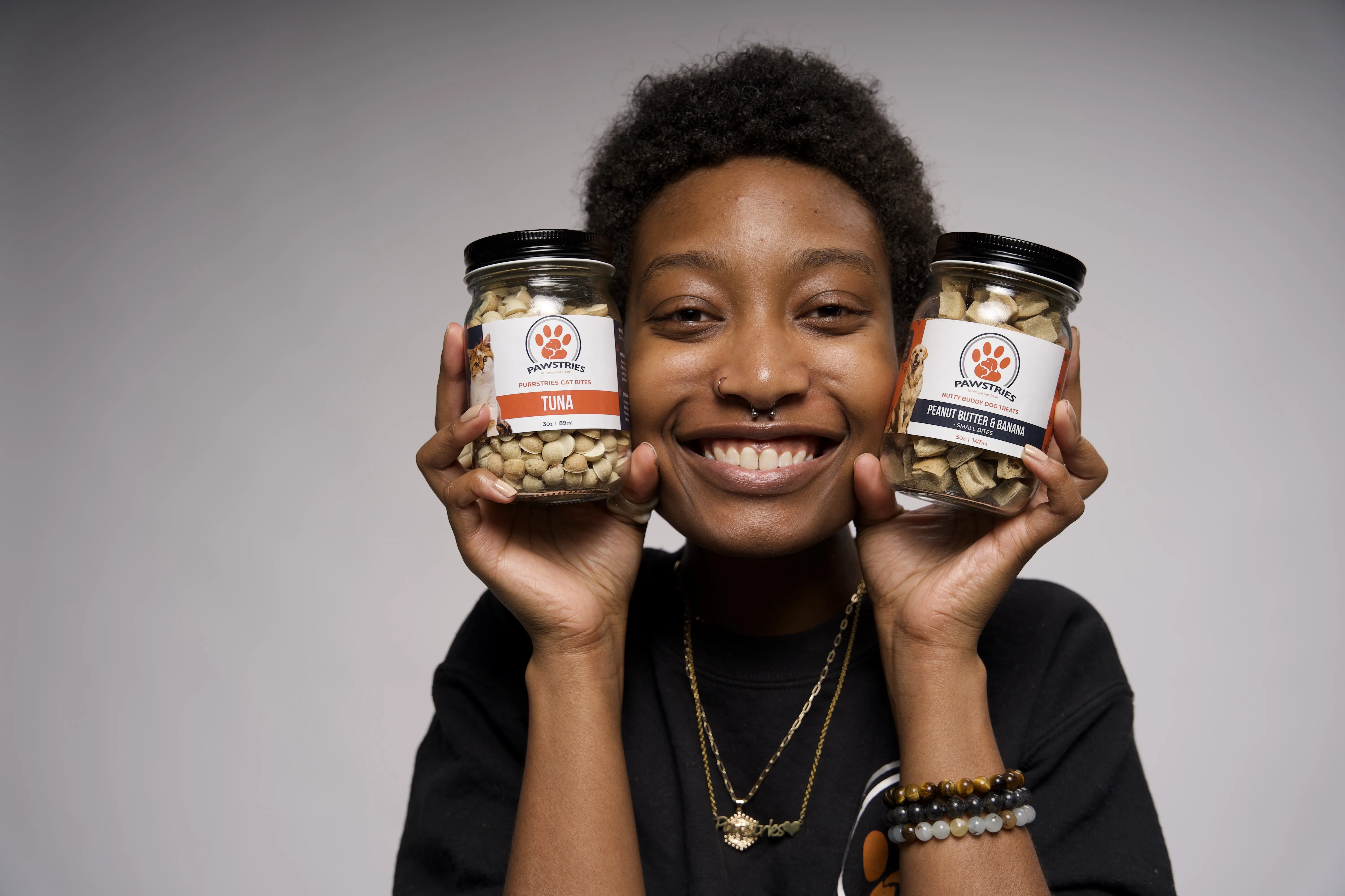African-American girl holding two glass jars filled with pet treats from Pawstries