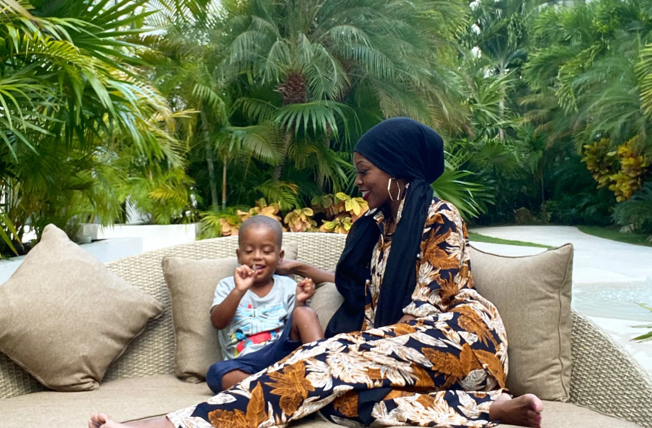 Founder with her son sitting in an outdoor area with trees in the background.